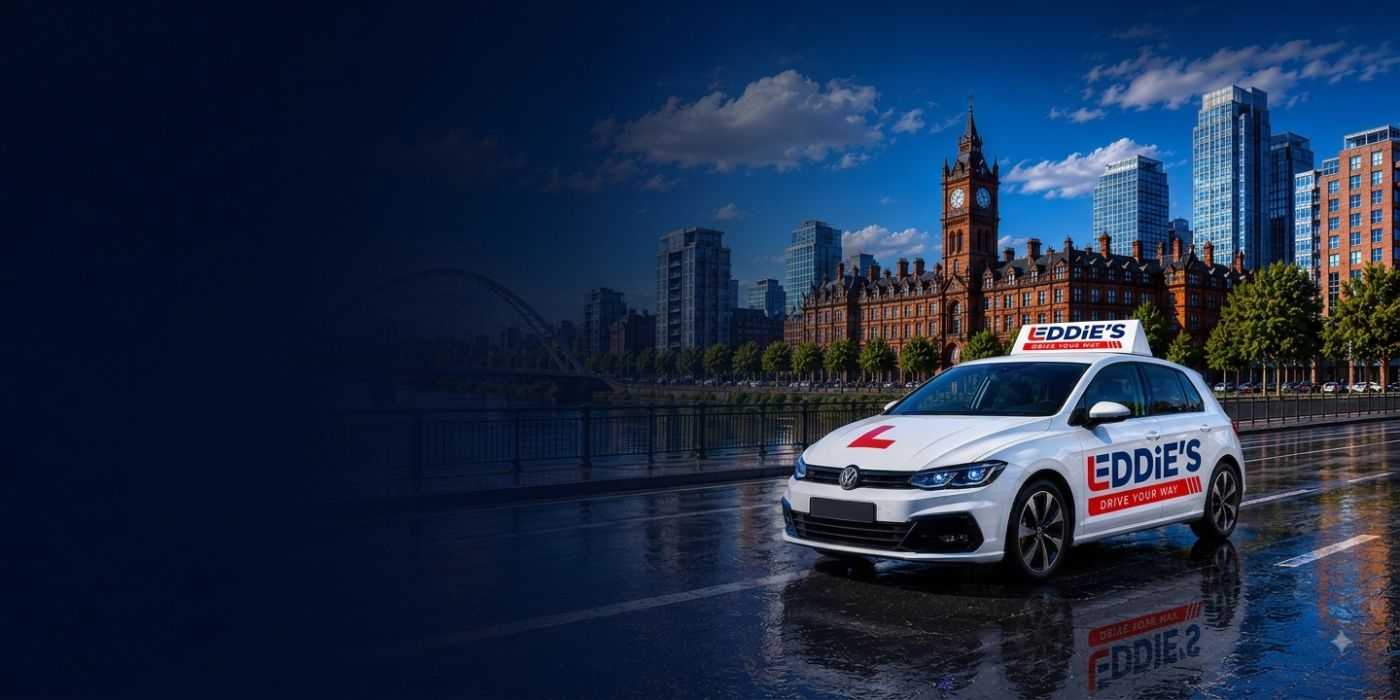 Eddie's School of Driving car, in its red and navy livery with an L-plate on the roof, on a road beside the water in Manchester.